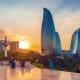 Flame Towers at sunset in Baku, Azerbaijan, viewed from a terrace with tourists and historic architecture in foreground